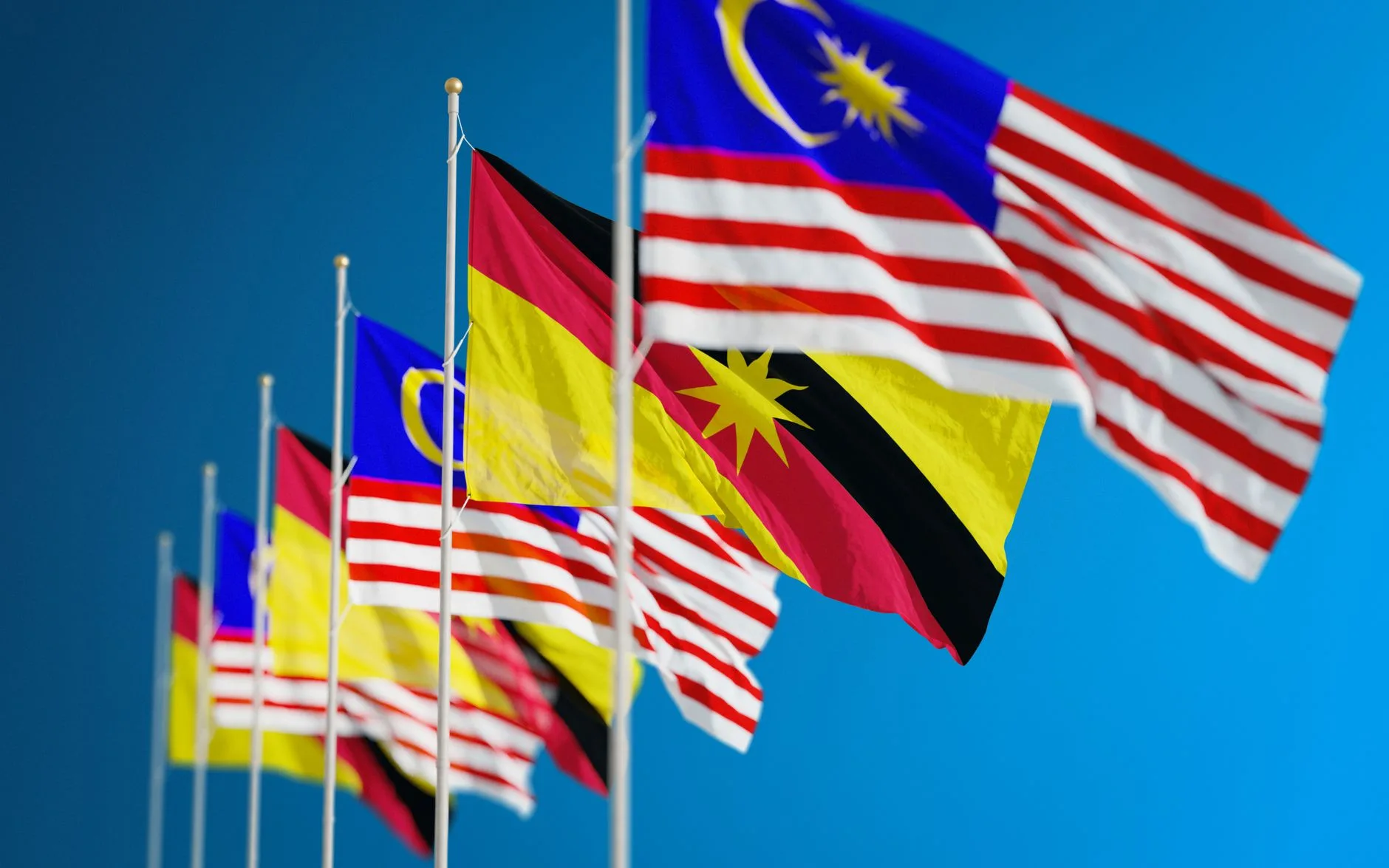 Bandiere della Malesia e di Sarawak sventolano insieme contro un cielo azzurro, simboleggiando unità e patriottismo.