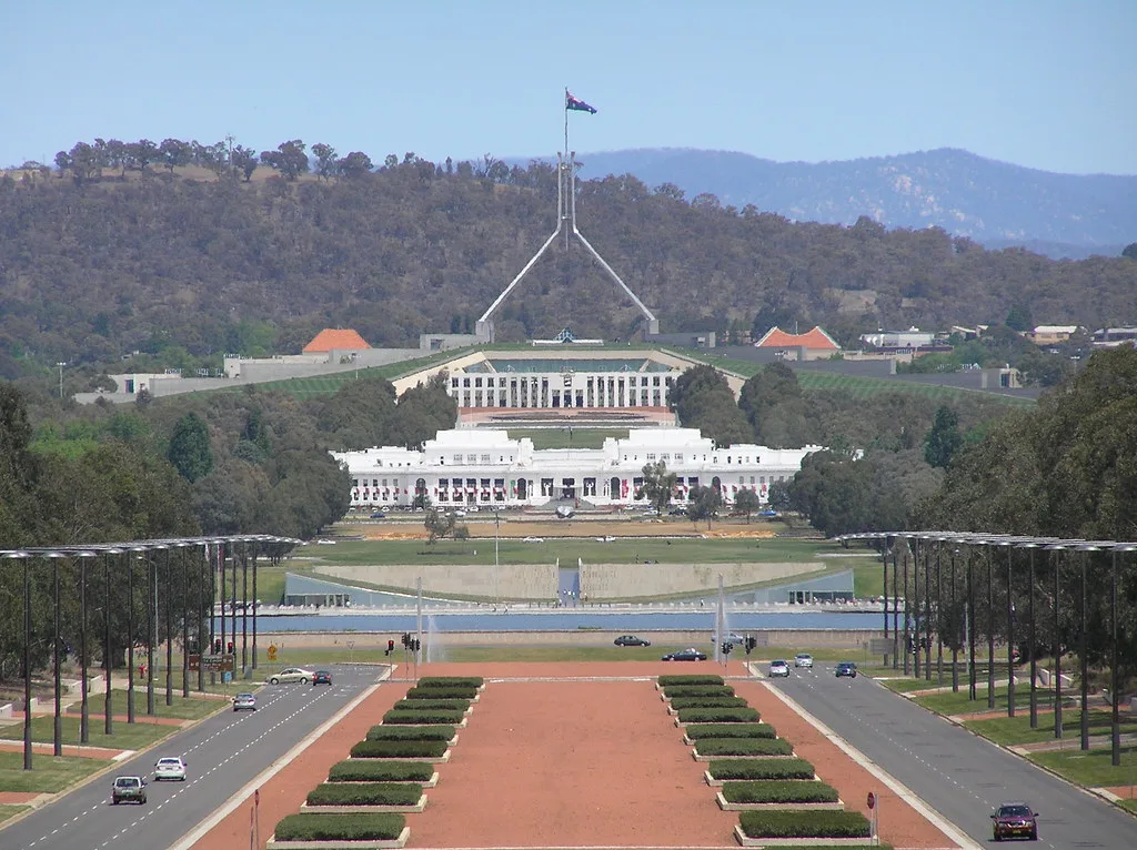 Il Parlamento australiano con la sua caratteristica cupola a boomerang circondato da giardini e colline boscose.