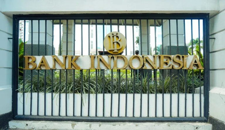 Cancellata d'ingresso della Bank Indonesia con logo dorato e scritta metallica, edificio vetrato sullo sfondo.