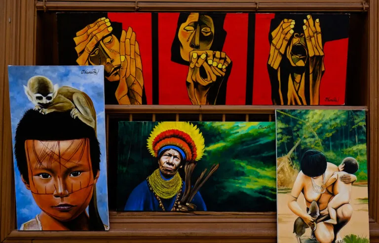 Opere d'arte figurative con volti e figure umane dipinti in stili geometrici e realistici, esposte in una galleria.