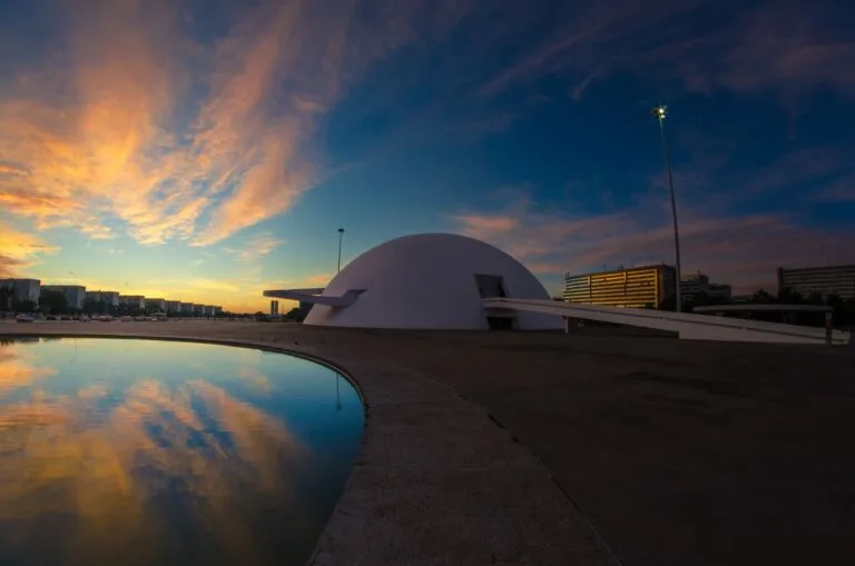 Tramonto su Brasília con il Museo Nazionale dalla forma cupolare riflesso nelle acque antistanti.