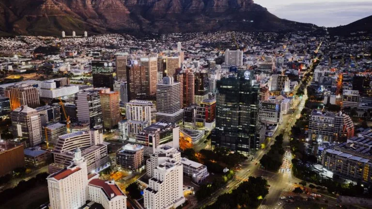 Veduta aerea di Città del Capo al tramonto con grattacieli e Table Mountain sullo sfondo.