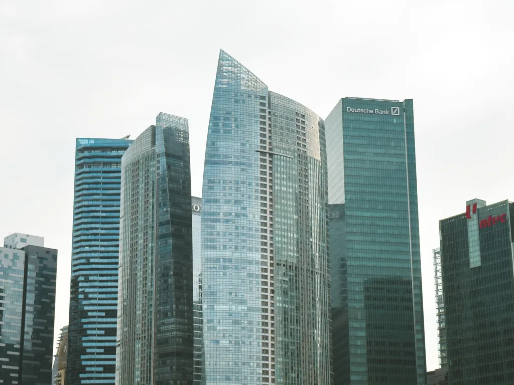 Grattacieli moderni di vetro e acciaio in un centro finanziario, con la sede di Deutsche Bank visibile a destra.