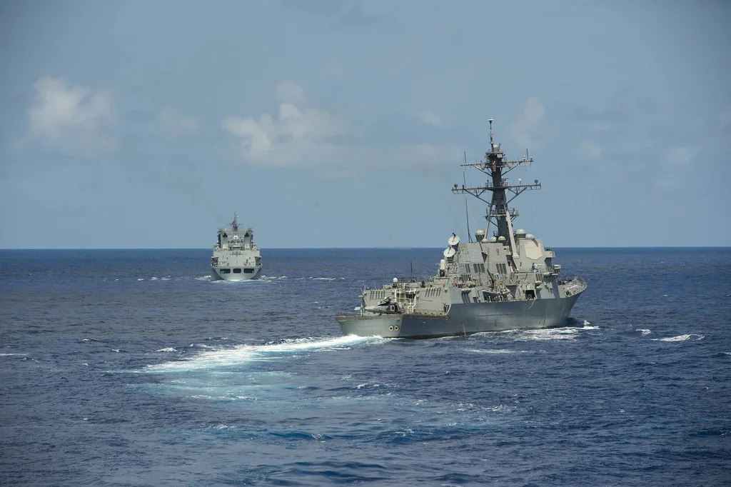 Una nave da guerra naviga nel Pacifico mentre una petroliera è visibile sullo sfondo.
