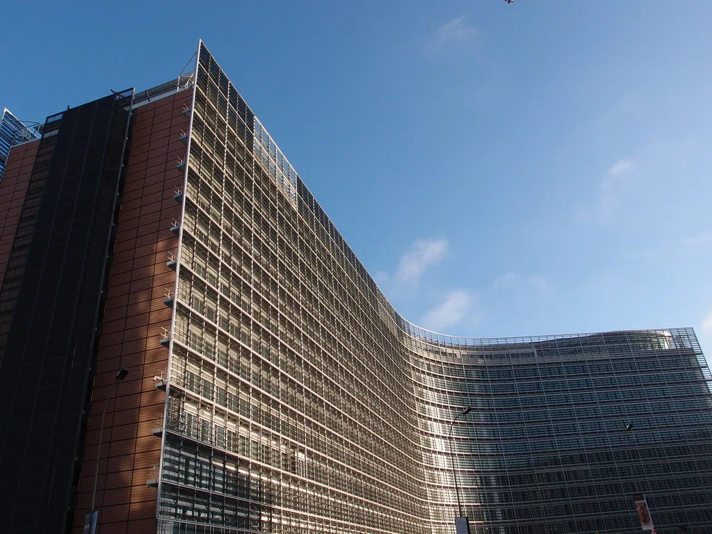 Edificio della Commissione europea a Bruxelles con facciata in vetro e laterizio rosso sotto cielo azzurro.