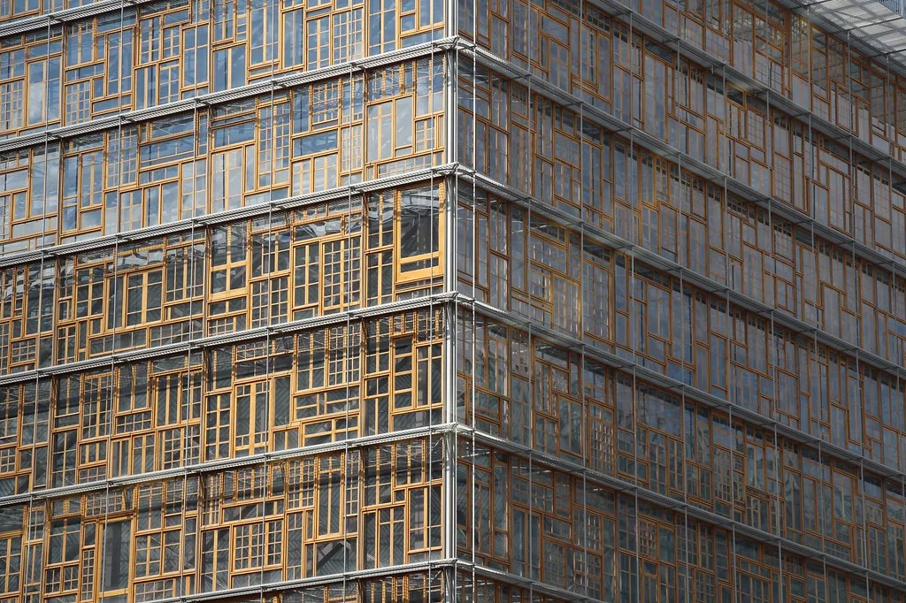 Grattacielo moderno con facciate in vetro e cornici metalliche dorate, angoli squadrati, architettura urbana contemporanea.