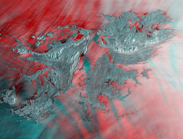 Arcipelago montuoso circondato da acque turchesi e zone desertiche rossastre riprese da satellite.