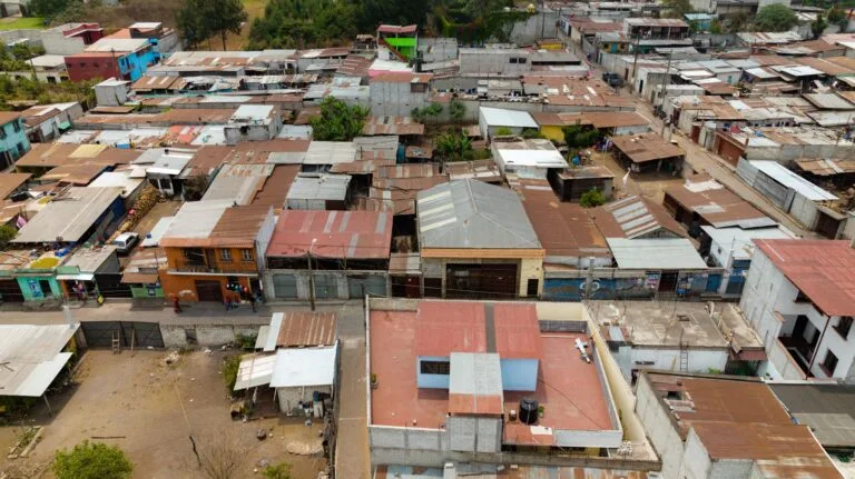 Veduta aerea di un insediamento urbano densamente popolato con abitazioni precarie in lamiera e cemento.