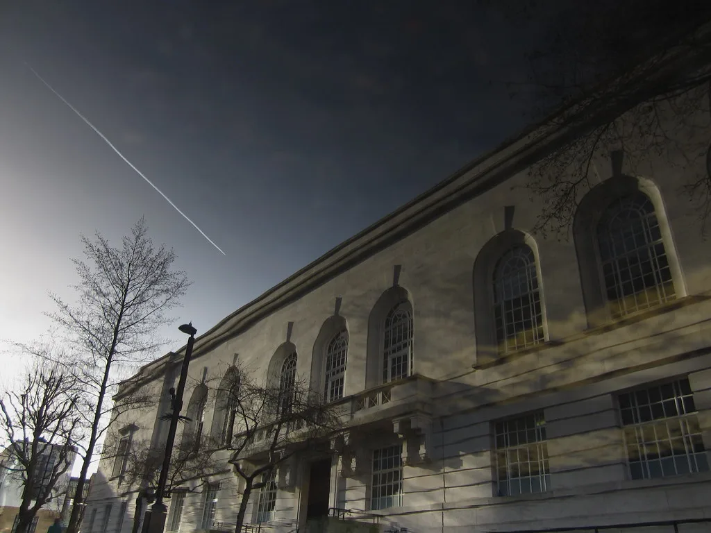 Edificio in stile neoclassico con finestre ad arco e facciata in pietra chiara sotto cielo sereno.