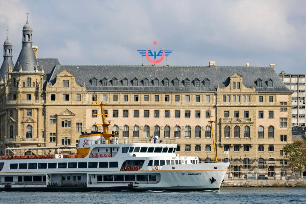 Traghetto bianco davanti al Terminal di Haydarpaşa, edificio storico giallo con tetto grigio sul Corno d'Oro.