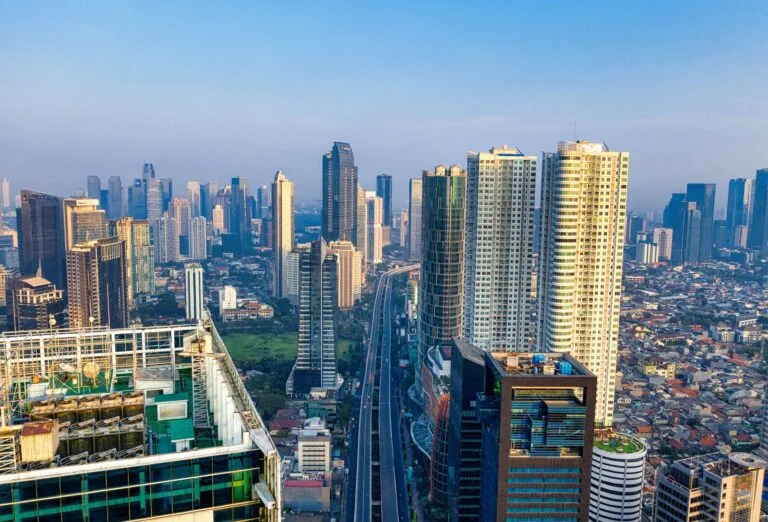 Skyline di grattacieli moderni a Giacarta con edifici alti circondati da costruzioni a bassa densità sotto cielo sereno.