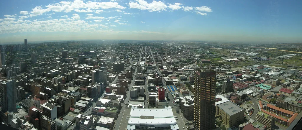 Veduta aerea di Johannesburg con grattacieli, strade rettilinee e estesa urbanizzazione sotto cielo sereno.