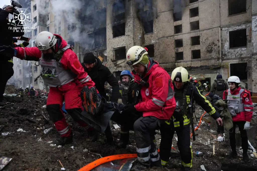 Squadre di soccorso in divise rosse e gialli trascinano una persona dalle macerie di un edificio danneggiato.