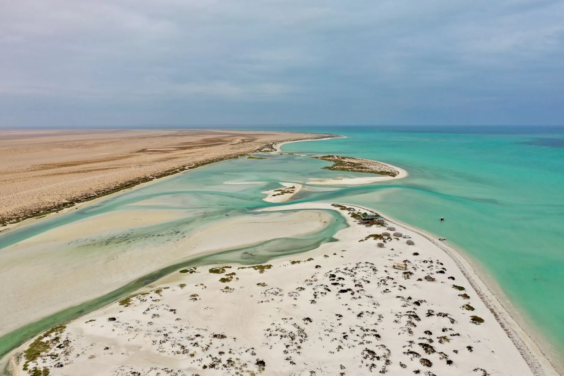Costa desertica con spiagge sabbiose, lagune azzurre e acque turchesi del Golfo Persico in una veduta aerea.