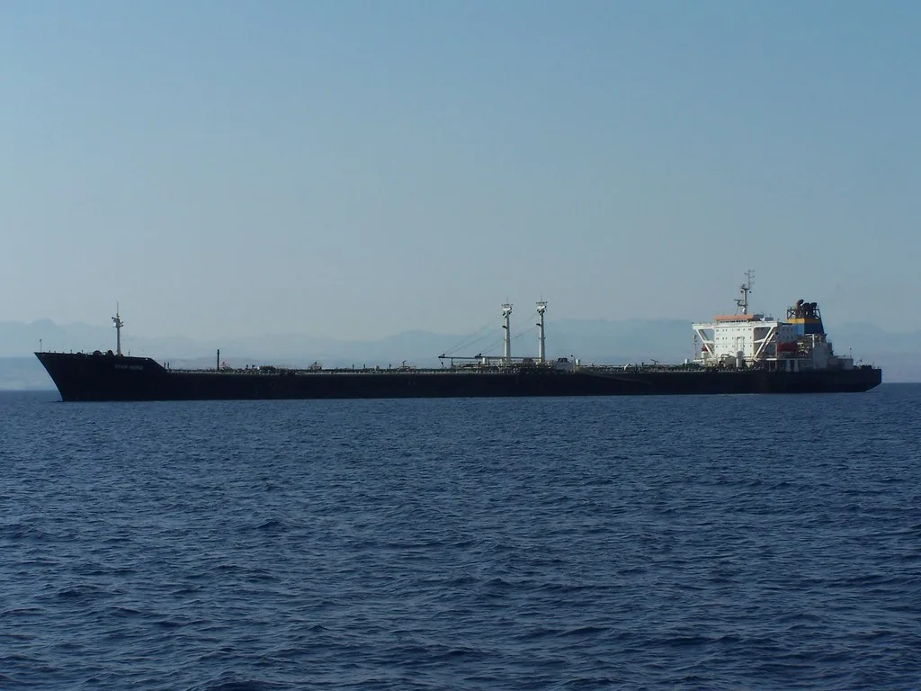 Petroliera in navigazione nel Mar Rosso con cielo sereno e costa sfocata sullo sfondo.