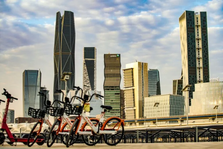 Skyline di grattacieli moderni con biciclette rosse in primo piano su una passerella.