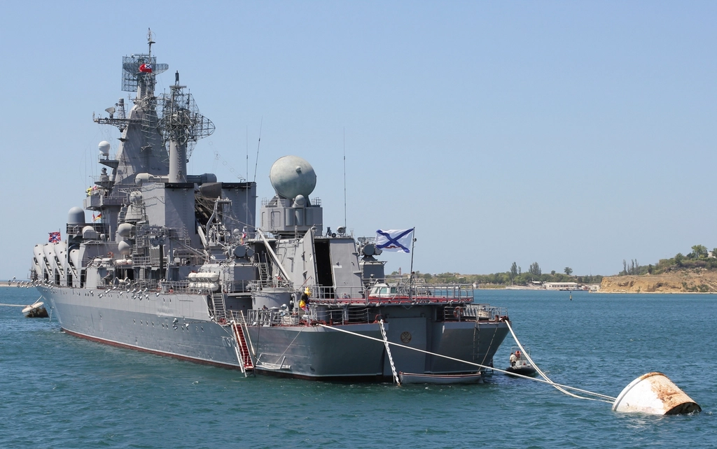 Nave militare russa in rada con sistema radar e torrette di fuoco, ormeggiata davanti a costa sabbiosa.