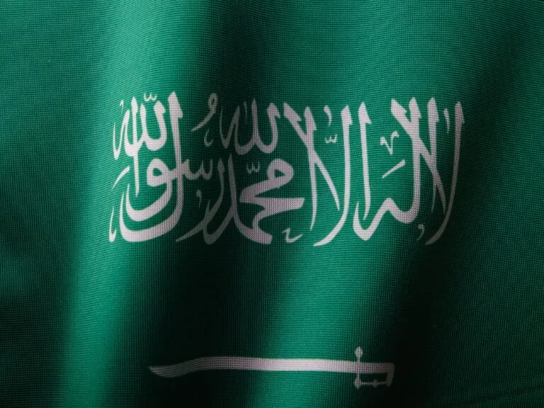 Bandiera dell'Arabia Saudita con scritte arabiche bianche in calligrafia su fondo verde e spada orizzontale.