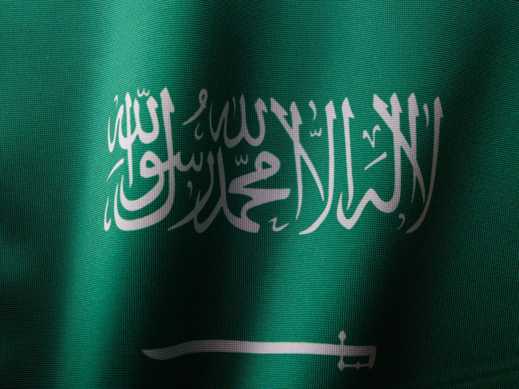 Bandiera dell'Arabia Saudita con scritte arabiche bianche in calligrafia su fondo verde e spada orizzontale.