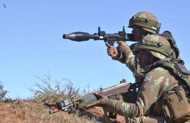 Soldati sudafricani in uniforme mimetica puntano un lanciagranate durante un'esercitazione militare.