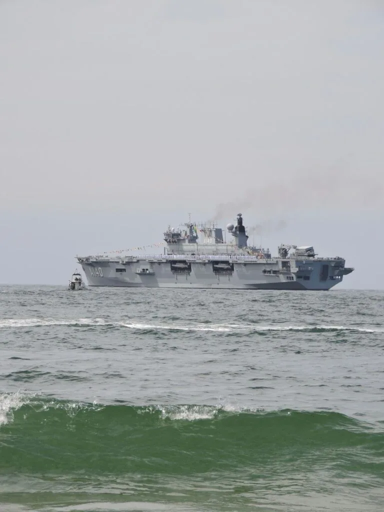 Nave portaelicotteri della Marina militare ancorata al largo con onde in primo piano.