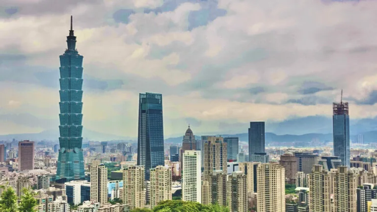 Lo skyline di Taipei con il Taipei 101 in primo piano tra gli edifici della metropoli e montagne sullo sfondo.