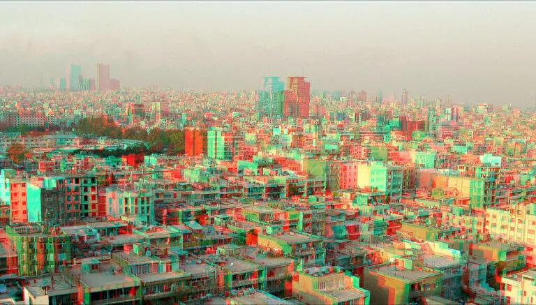 Panorama urbano di Teheran con effetto anaglifo 3D in rosso e ciano, mostrando la densità abitativa della capitale iraniana.