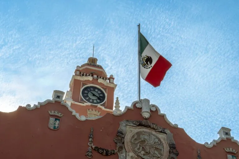 Torre dell'orologio del Palazzo Municipale con bandiera messicana e stemma dell'aquila su edificio coloniale rosso.