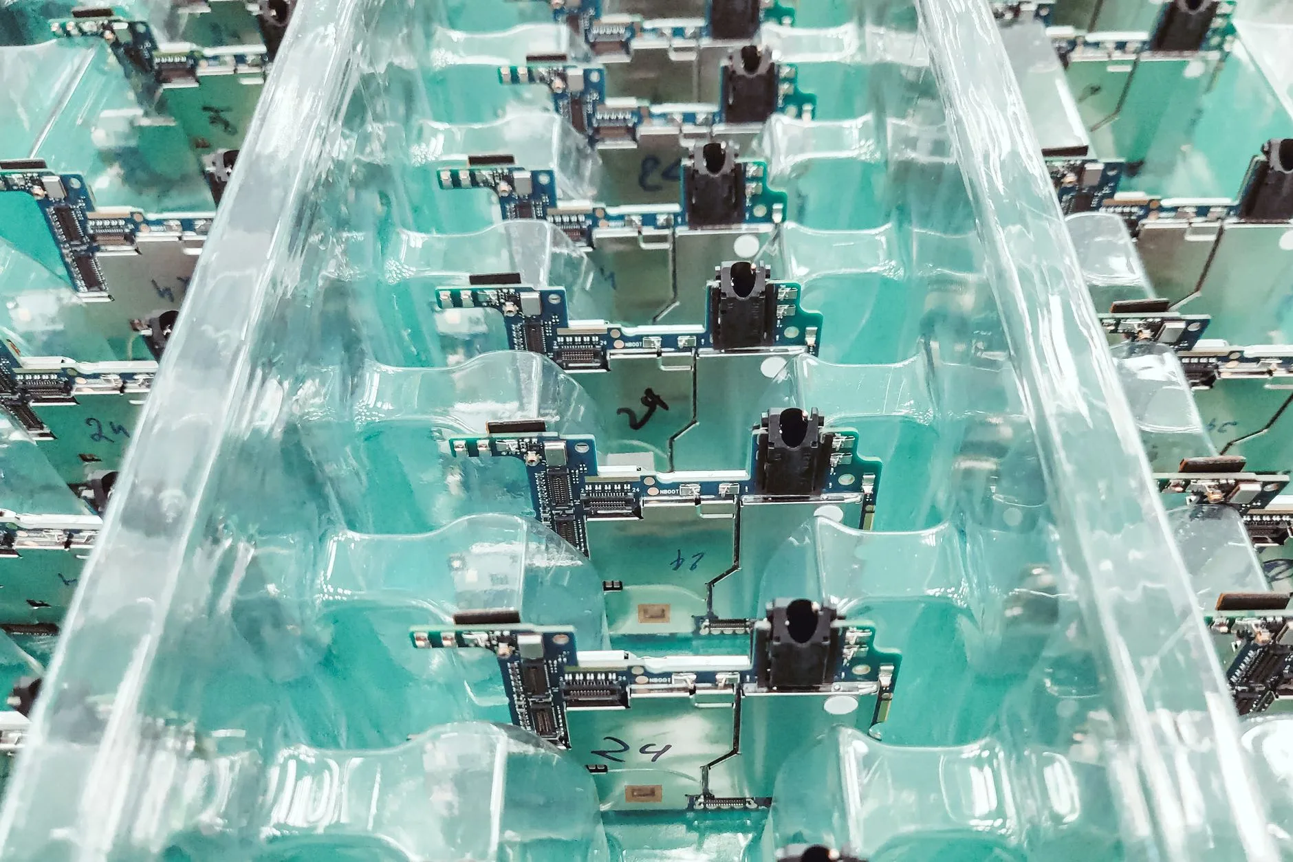 File di schede elettroniche verdi con componenti e connessioni allineate in una linea di produzione.