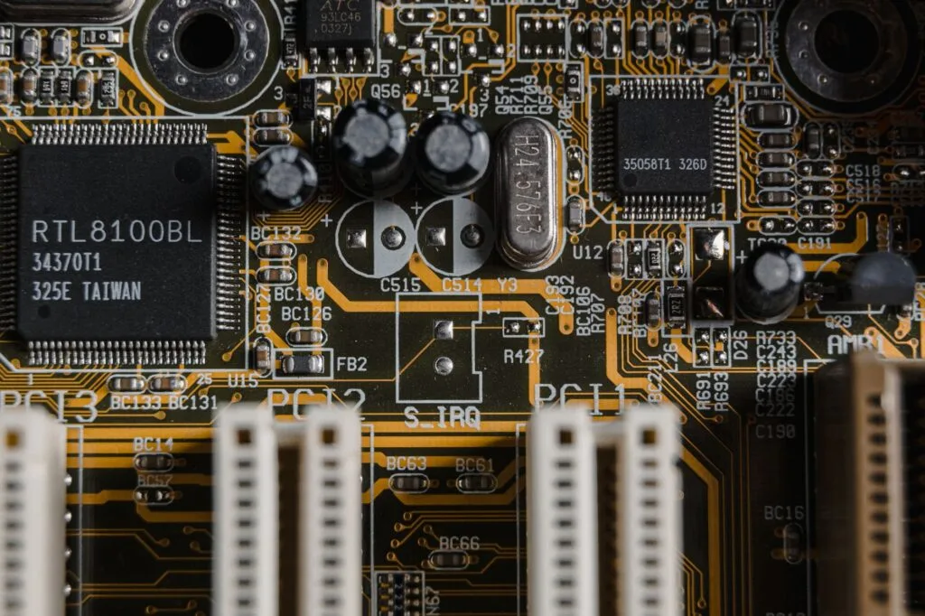 Circuito integrato di una scheda madre con microchip, condensatori e connettori su base dorata e nera.