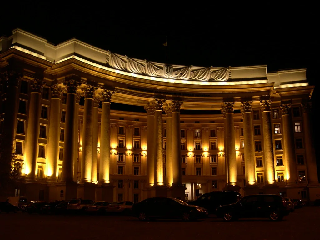 Edificio neoclassico illuminato di notte con colonne doriche e decorazioni in stile classico sulla cornice.