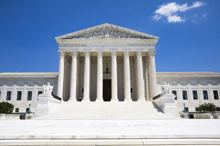 Facciata della Corte Suprema degli Stati Uniti con colonne ioniche e scalinata, cielo sereno sullo sfondo.