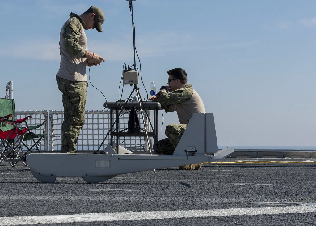 Militari in uniforme mimetica operano su un'antenna di comunicazione su una piattaforma navale.