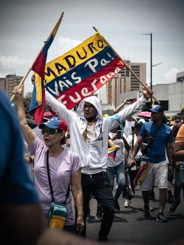 Manifestanti in strada brandiscono la bandiera nazionale venezuelana e striscioni di protesta contro il governo.
