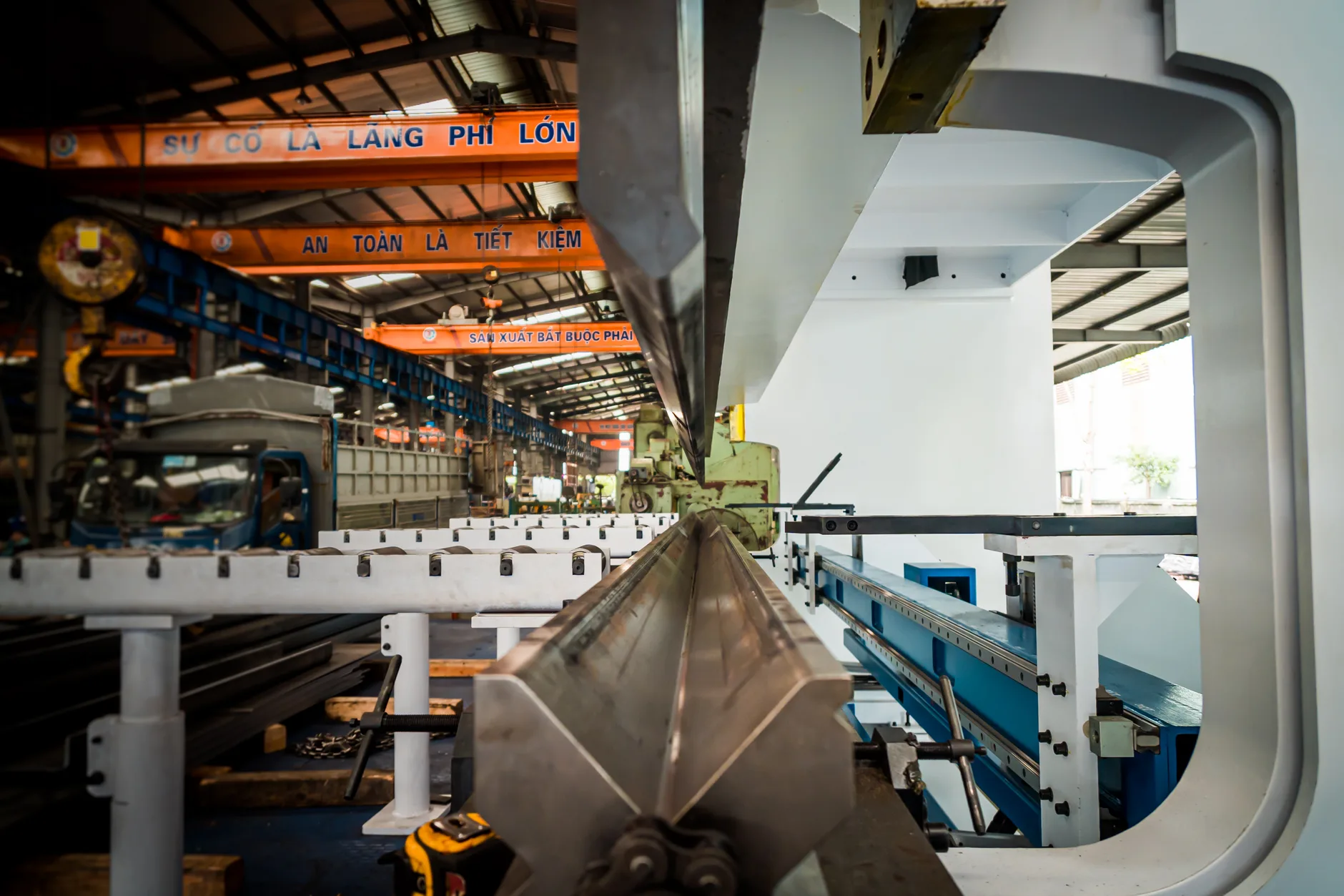 Interno di stabilimento industriale con sistemi di sollevamento e conveyor in metallo, insegne in vietnamita.