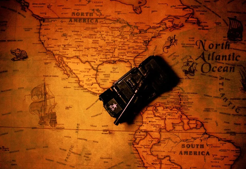 Una mappa antica dell'America del Nord con una riproduzione di carro armato in miniatura posizionata sopra il continente.