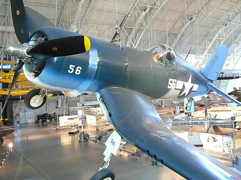 Caccia F4U Corsair blu della marina statunitense esposto in hangar, con numero di coda 56 e stella americana.